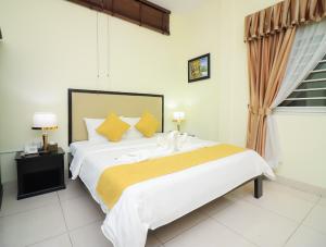 a bedroom with a large white bed with yellow pillows at Milan Hotel & Restaurant in Phnom Penh