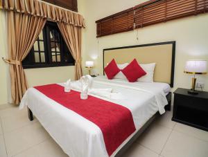 a bedroom with a large white bed with red pillows at Milan Hotel & Restaurant in Phnom Penh
