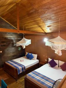Dos camas en una habitación con paredes de madera. en Sigiriya Free View Tree House & Villa, en Sigiriya