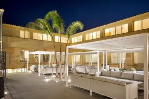 a patio with white furniture and palm trees in front of a building at Hotel San Teodoro in San Teodoro