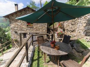 a table with a green umbrella on a patio at Masia Can Constans in Queralbs