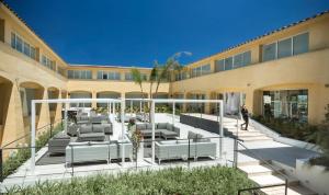 a building with a patio with lounge chairs in it at Hotel San Teodoro in San Teodoro