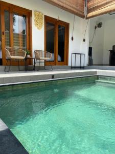 - une piscine avec 2 chaises en face d'une maison dans l'établissement Villa Lestari by MentariPro Bali, à Lovina