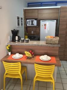 een keuken met twee stoelen en een tafel met fruit erop bij Costeira Praia - Belo Flat in Natal