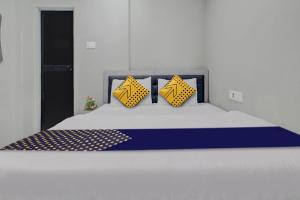 a bed with yellow and blue pillows on it at Hotel O The VNP Inn in Sakardarā