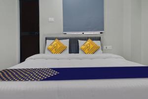 a bed with yellow and blue pillows on it at Hotel O The VNP Inn in Sakardarā