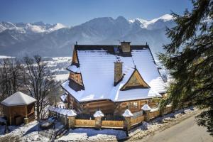 a house covered in snow with mountains in the background at Willa Irena in Kościelisko