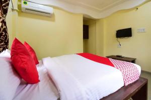 a bedroom with a bed with red and white pillows at Hotel O Gokul Lodging in Pune