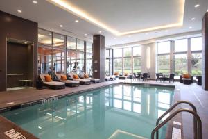 una piscina en un edificio con sillas y mesas en The Hotel at Arundel Preserve en Hanover