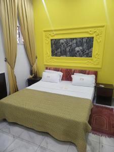 ein Schlafzimmer mit einem großen Bett mit einer gelben Wand in der Unterkunft Étoile de Justin in Pointe-Noire