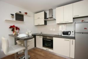 a kitchen with white cabinets and a table with a microwave at Apartments Zagreb Schone in Zagreb