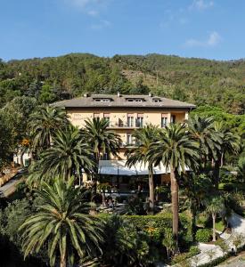 a large building with palm trees in front of it at Hotel Villa Adriana in Monterosso al Mare