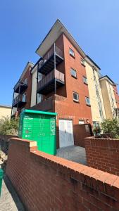 a brick building with a green garage in front of it at Spacious Ground Floor 2-Bed Flat - Patio, Parking - By Habitats in Southampton
