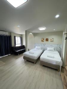 a bedroom with two beds and a couch at ปากช่องอพาร์ทเม้นท์ in Pak Chong