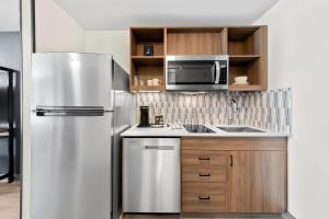 Una cocina con refrigerador de acero inoxidable y microondas. en Everhome Suites San Bernardino - Loma Linda, en San Bernardino