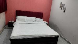a bedroom with a bed with white sheets and a red wall at HOTEL O SKY in Phundardih