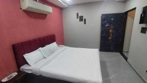 a bedroom with a white bed with a red wall at HOTEL O SKY in Phundardih