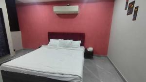 a bedroom with a large bed with a red wall at HOTEL O SKY in Phundardih