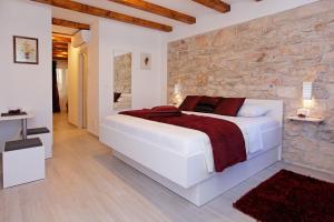 a bedroom with a large white bed and a stone wall at Luxory D-Rooms in Vela Luka