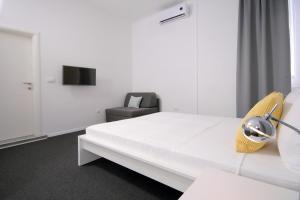 a hotel room with a white bed and a chair at Charm Apartments And Rooms in Trogir