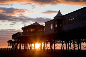 a pier with the sun setting behind it at EsJays at Knowles House in Lytham St Annes