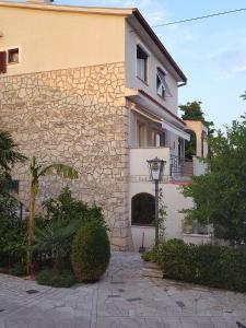 aige and white building with a stone wall at Villa Feral Apartments in Crikvenica