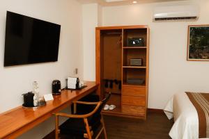 a bedroom with a desk with a television and a bed at Hotel Téneka in Xilitla