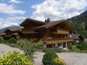 a large wooden house with mountains in the background at Farfalla in Gstaad