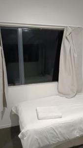 a white bed in a room with a window at 4 Beds in 2 Bedroom Garden Chalet, Rotorua in Rotorua +1 photo
