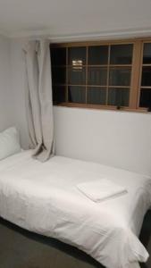 a white bed in a room with a window at 4 Beds in 2 Bedroom Garden Chalet, Rotorua in Rotorua