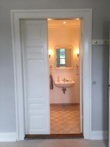 baño con lavabo, espejo y puerta en Birkum BB, en Birkum