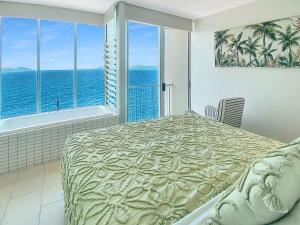 a bedroom with a bed with a view of the ocean at 1 Bright Point Apartment 4305 in Nelly Bay +10 photos
