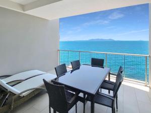 a balcony with a table and chairs and the ocean at 1 Bright Point Apartment 4305 in Nelly Bay