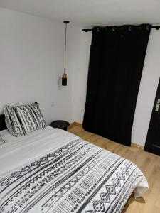 1 dormitorio con 1 cama con cortina negra en Elégance, sobriété, T2 centre-ville, en Le Mans
