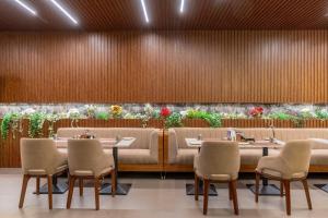 a restaurant with tables and chairs and plants at Hotel Diyanvi in Mysore