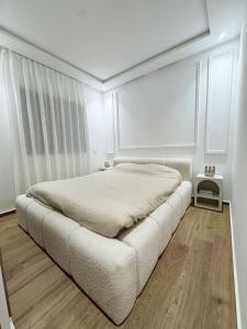 马拉喀什Appartement de Luxe 3 Chambres avec piscine au centre的一间铺有木地板的白色卧室,配有一张床