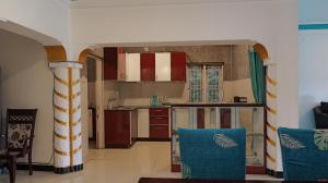 a kitchen with red and white cabinets and blue chairs at Happy Villa By Eden Luxury Stay in Ooty
