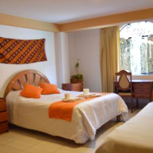 una camera d'albergo con letto e cuscini arancioni di Casa De paz a Písac