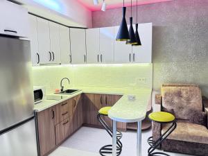 a kitchen with white cabinets and a table and a sink at Уютная квартира in Almaty +1 photo