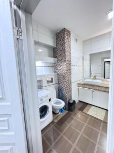 a bathroom with a washer and a toilet and a sink at Уютная квартира in Almaty