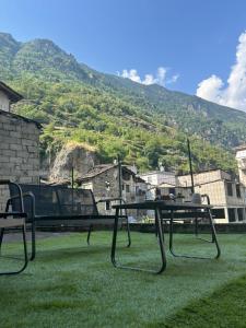 a table and a chair on the grass with a mountain at Casa Dolce Caty in Grosio +5 photos