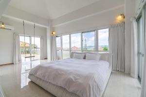 1 dormitorio blanco con 1 cama grande y ventanas grandes en Sommelier Villa ISHIGAKI, en Ishigaki Island