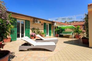 eine Terrasse mit zwei weißen Stühlen und einem grünen Sonnenschirm in der Unterkunft Tetto Fiorito in Castellammare di Stabia