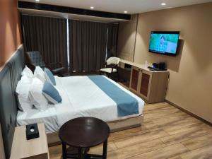 a hotel room with a bed and a flat screen tv at Hotel Su-Casa in Bhavnagar