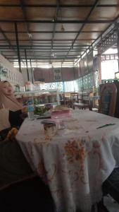 a woman sitting at a table with a white table cloth at Hotel Grand Orindo in Tjakranegara