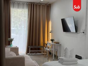 a hotel room with a bed and a tv on a wall at Happy One-Bedroom Stay in Hat Yai in Ban Thung Ngai