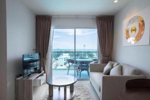 Una sala de estar con un sofá, un televisor y una mesa. en GrandBlue Condo 506, en Ban Tha Fat