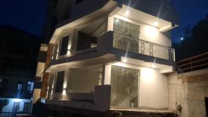 a large white building with a balcony at night at Hotel Anji Solan Hills in Solan