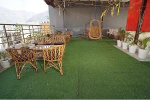 Un grupo de mesas y sillas en un balcón con césped verde. en Hotel Luxury Heaven, en Rishīkesh