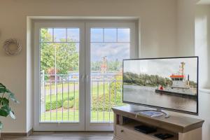 a living room with a flat screen tv in front of a window at Villa Kanalblick, Ausguck in Oldenbüttel